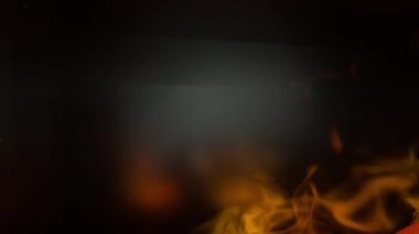 Şöminedeki yangından yükselen karanlık bir arka planda duman.