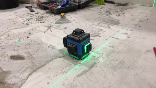 Laser level projects green lines onto the cement floor — Stockvideo