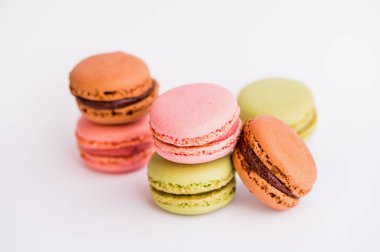 Pembe, yeşil ve kahverengi altı badem kurabiyesi beyaz arka plana karşı.