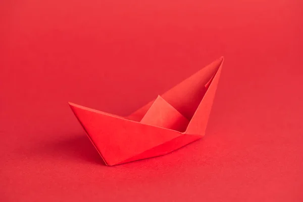 single red paper boat on red background with copy space
