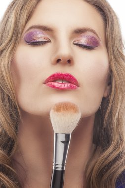 Genç sarışın bir kadın makyaj fırçası ile