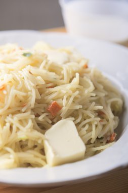 Beyaz plaka üzerine tereyağı parçası ile makarna