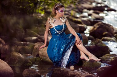 Sanatsal Kafkasyalı Sarışın Yüzünde Askılı Deniz Kızı Rocky Shore 'da Mavi Islak Elbise Giyiyor. Yatay Resim Kompozisyonu