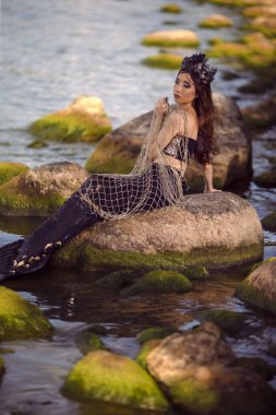 Rocky Deniz Kıyısı 'nda Ağlı Şehvetli Denizkızı, Deniz kabuğu süslenmiş taç ve ince gövdesine siyah parlak kuyruk takarak, Deniz Kraliçesi kılığına girmiş. Dikey Resim Yönlendirmesi