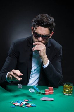 Kumarhane Kavramları. Beyaz tenli yakışıklı Poker oyuncusu poker masasında fiş ve kartlarla bahis oynuyordu. Dikey Resim