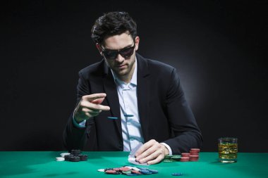 Kumar Konseptleri. Beyaz tenli yakışıklı Poker oyuncusu poker masasında fiş ve kartlarla bahis oynuyordu. Yatay Resim Kompozisyonu
