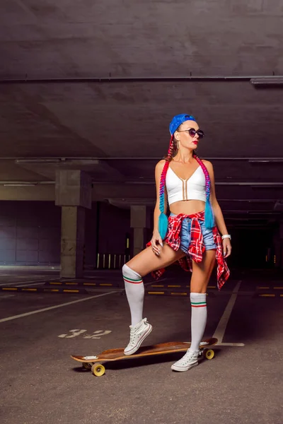 Hippi Kadın Kaykaycı Şortlu ve Beyaz Çoraplı Dışarıdaki Boş Otopark Sisteminde Uzuntahta Sürüşü Uygulaması. Dikey Resim Kompozisyonu