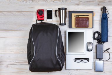 Flat Lays Kavramları. Top View Sırt Çantası Dizüstü bilgisayarlı ve Tabletli, Not Defteri ve Aksesuarlı Cep Telefonu Ahşap Arkaplan Üzerinde. Seyahat Hayat Aksesuarları kavramı