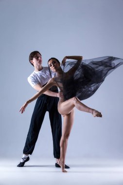 Dans fotoğrafçılığı fikirleri. Profesyonel Bale Çifti Stüdyoda Birlikte Gösteri Yaparken Kız Beyaz Arkaplan Karşısında Vücut Kıyafeti Giyiyor. Dikey Resim Kompozisyonu