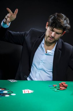 Genç, duygusal, beyaz tenli Brunet Poker oyuncusu poker masasında patates kızartması ve kartlarla oynarken. Dikey Resim Kompozisyonu