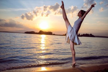 Japon Bale Dansçısı ile Tutku ve Aşk Okyanus Dalgaları 'nda Gümüş Taç Dansçısı ve Denizde Resim Yapan Gün Batımına Karşı Kaldırılmış Ellerle Bale Pas Gösteriyor. Yatay Resim