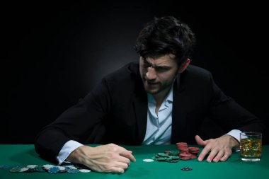 Pocker Masası 'nda Cipslerle oynayan konsantre, yakışıklı, beyaz tenli Brunet Genç Poker oyuncusu. Yatay Resim Yönlendirmesi