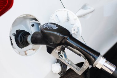 Benzin istasyonunda yakıt deposuna yerleştirilmiş beyaz araba benzinle dolduruluyor. Yatay Görüntü