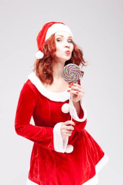 Yeni yıl kavramları. Kafkasyalı kızıl saçlı Santa Helper 'ın portresi. Renkli Tatlı Lolipop Şeker-Erik Şekeri. Dikey Resim