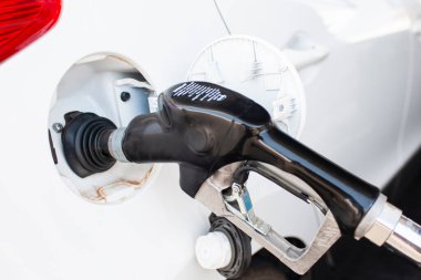 Tavel Kavramları. Benzin istasyonunda yakıt deposuna yerleştirilmiş beyaz araba benzinle dolduruluyor. Yatay Resim