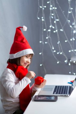 Evde ve Evinden Çalışmalar Yaparken Dijital Dizüstü Bilgisayarda Noel Baba Şapkası Giyen Pozitif ve Mutlu Gülümseyen Kafkasyalı Kız Bilgisayarı Evinde ve Dikey Kompozisyonda Bilgisayar Kullanıyor