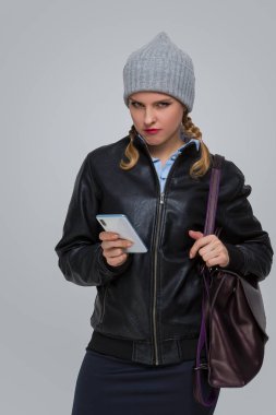 Yaşam stili fikirleri. Genç Üzgün Bunalımlı Kafkasyalı Sıcak Şapkalı Sarışın Kız ve Cep Telefonu ve Sırt çantalı Deri Ceket. Dikey Çekim