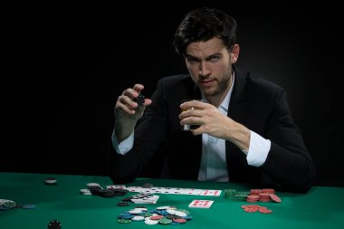 Alkol içerken elinde cips ve kartlarla poker masasında konsantre, yakışıklı, beyaz tenli, Brunet Genç Poker oyuncusu. Yatay Resim Kompozisyonu