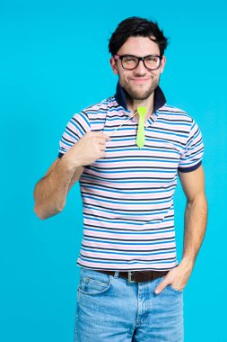 Komik, gülümseyen, beyaz, yakışıklı, sanatsal, yeşil kravatlı, kusursuz mavi arka plana karşı resmi giyinen adam. Dikey Çekim