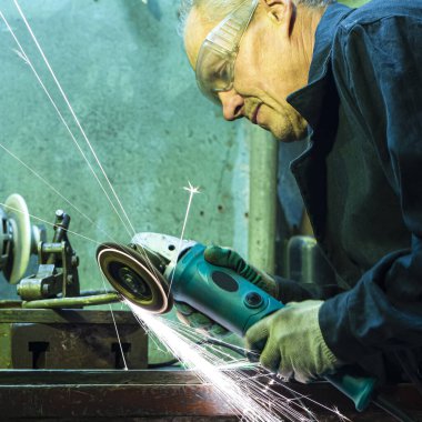 Metal işleme konseptleri. Atölyede Kıvılcımlarla Metal Çalışmaları İçin Gringer Aletleri Kullanan Koruyucu Eldiven Giyen Erkek Profesyonel Sporcu. Kare Resim