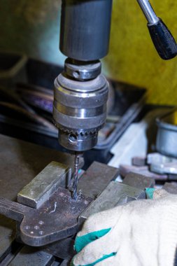 Profesyonel fitter atölyede Uzun Matkapla Metal Delikler Açmak için Metal Delme Makinesi kullanıyor. Dikey Çekim
