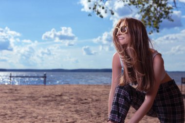 Güneşli bir günde Sahil ya da Deniz Kıyısı Dış Hatları 'nda Günlük Sokak Giysileri pozu veren Beyaz Sarışın Kız' ın Yazlık Portresi. Yatay resim