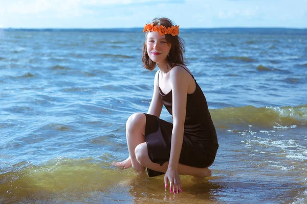 Gündüz vakti deniz kıyısında çiçek desenli çelenk giyerken deniz dalgalarında dinlenen günlük giyinen Kafkasyalı Esmer Kız. Yatay Resim