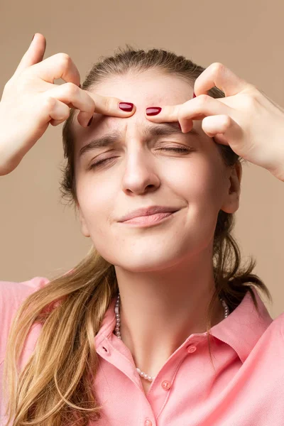 Cilt ve Sağlık Sorunları. Bej 'e karşı parmaklarıyla kabarcık sıkma problemleri olan Genç Duygusal Kafkas Sarışın Kadın portresi. Dikey Resim