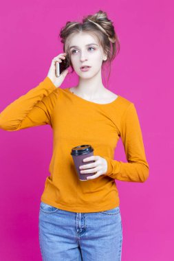 Bir Aktif Kafkas Sarışın Kız, Pembe Arkaplan 'ın üzerinde konuşurken ve içerken cep telefonu tutuyor. Dikey Resim