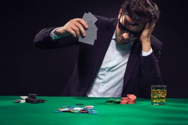Oyun Kavramları. Bunalımlı Kafkas Brunet Poker Oyuncusuyla Poker Masası 'nda. Duygusal olarak bir yığın kart atarken. Yatay Görüntü