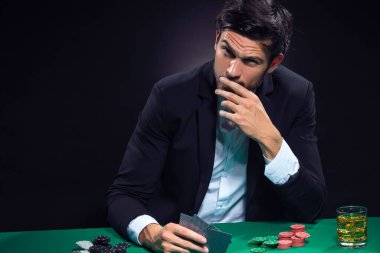 Bunalımlı Kafkas Brunet Poker Oyuncusuyla Poker Masası 'nda Cipsler ve Kartlarla Düşünerek Kartlarla Otururken. Yatay Resim Kompozisyonu