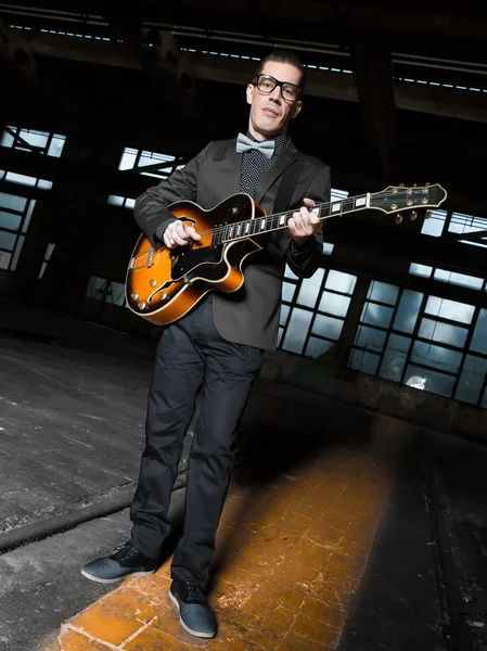 建物の低光の中で放棄された若いギタリスト — ストック写真