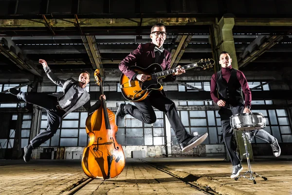 Rock band jumps into the air in an industrial building — Stock Photo, Image