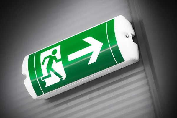 Green emergency exit sign showing the way to escape — Stock Photo, Image