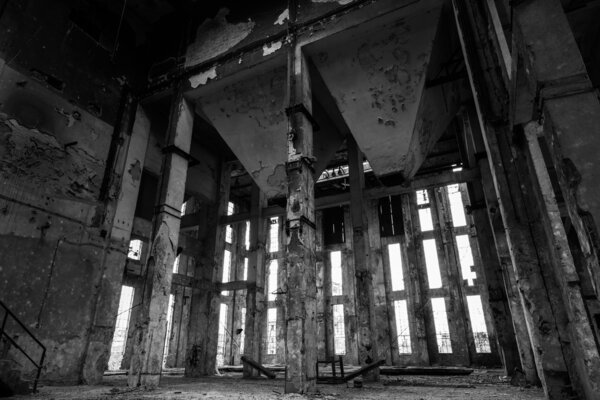 A desolate old industrial building inside with many windows