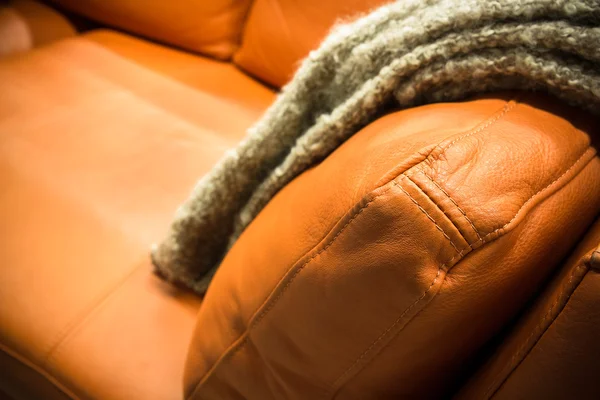 Šedou deku přehozenou přes kožené pohovce — Stock fotografie