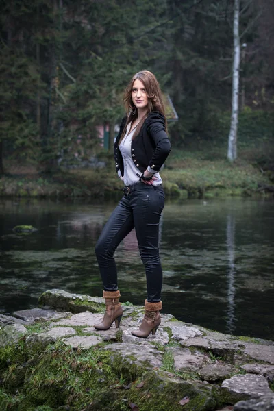 Young woman in jacket standing and posing at the lake — Stock Photo, Image