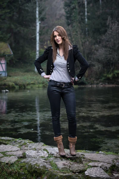 Mujer joven con chaqueta de pie y posando en el lago — Foto de Stock