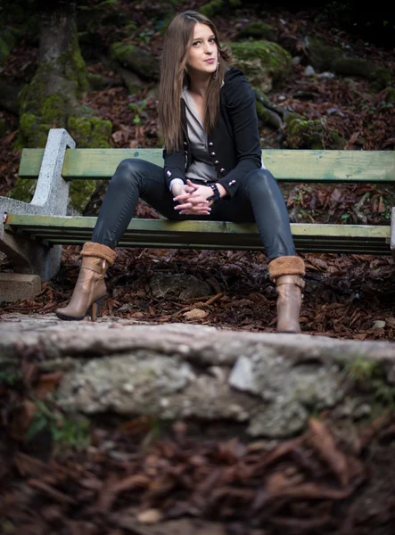 Молодая женщина в пиджаке сидит на скамейке — стоковое фото