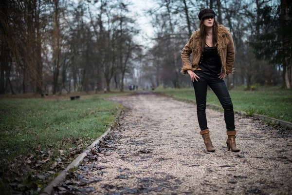 Mujer joven con chaqueta de pie y posando en el bosque —  Fotos de Stock