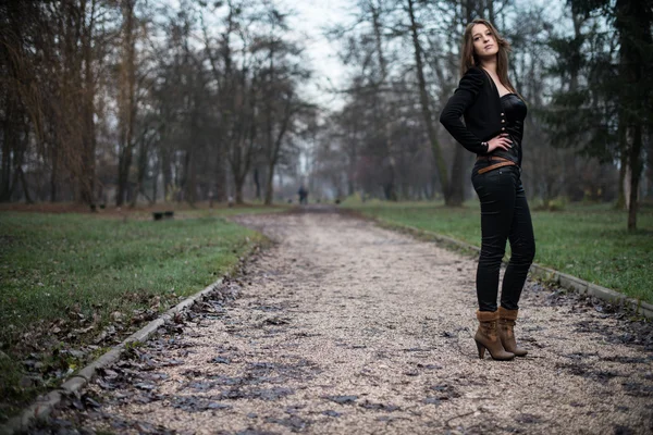 Mujer joven con chaqueta de pie y posando en el bosque —  Fotos de Stock