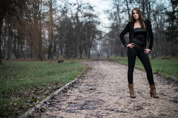 Mujer joven con chaqueta de pie y posando en el bosque — Foto de Stock