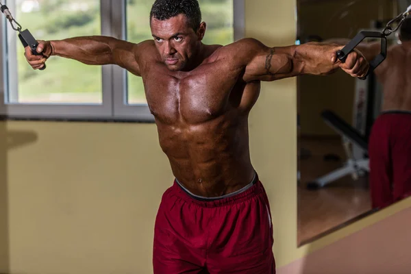 Shirtless body builder doing standing press white cable for chest — Stock Photo, Image