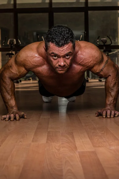 Culturista masculino haciendo flexiones en el suelo — Foto de Stock