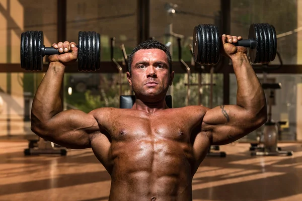 Male bodybuilder doing shoulder press whit dumbbell — Stock Photo, Image