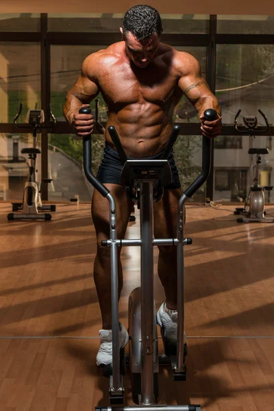 Male bodybuilder using the elliptical machine
