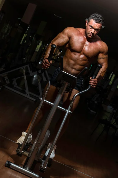 Männlicher Bodybuilder mit der elliptischen Maschine — Stockfoto