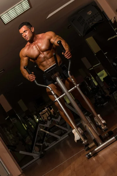 Männlicher Bodybuilder mit der elliptischen Maschine — Stockfoto