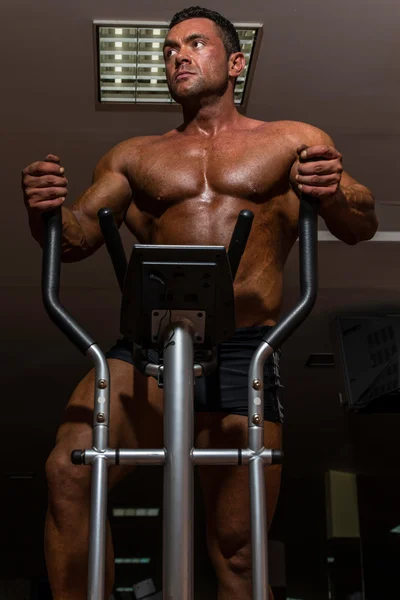 Männlicher Bodybuilder mit der elliptischen Maschine — Stockfoto