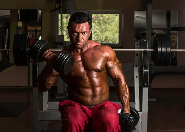 Fisicoculturista sin camisa haciendo ejercicio pesado para bíceps — Foto de Stock